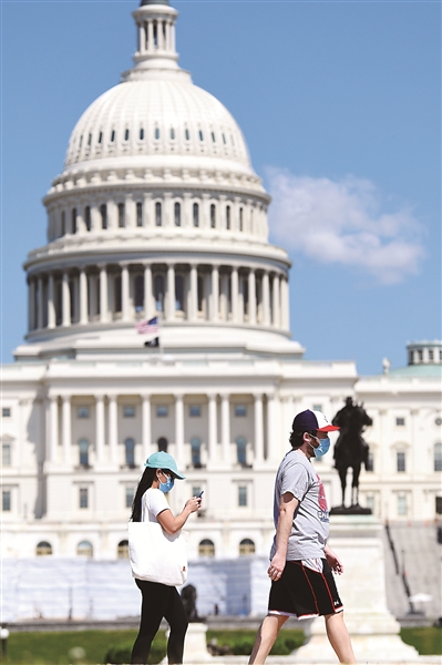在美国首都华盛顿，戴口罩的行人从国会大厦附近走过。 新华社记者 刘杰 摄